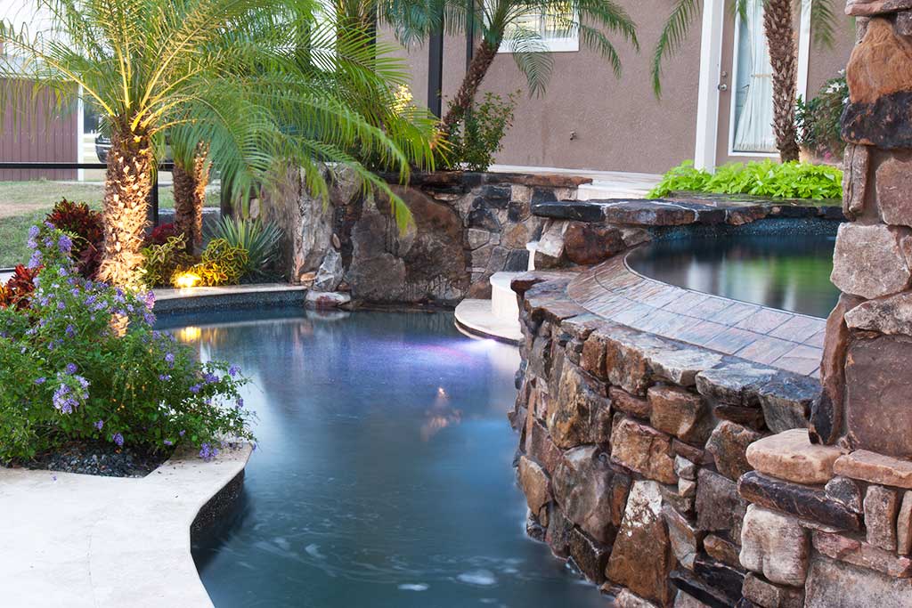 Lagoon pool with spa and infinity edge and a natural stone grotto, swim up barand outdoor kitchen and fireplace