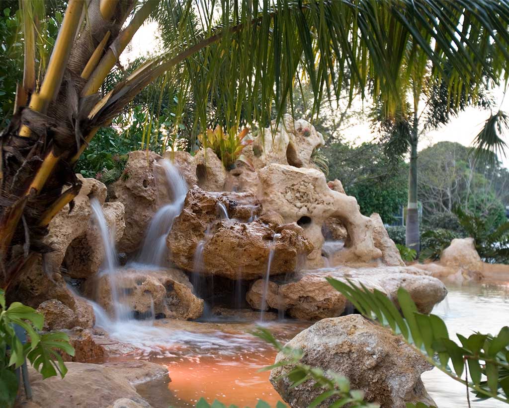 Natural lagoon pool with Florida Limestone waterfalls and a sand bottom in Englewood, Florida