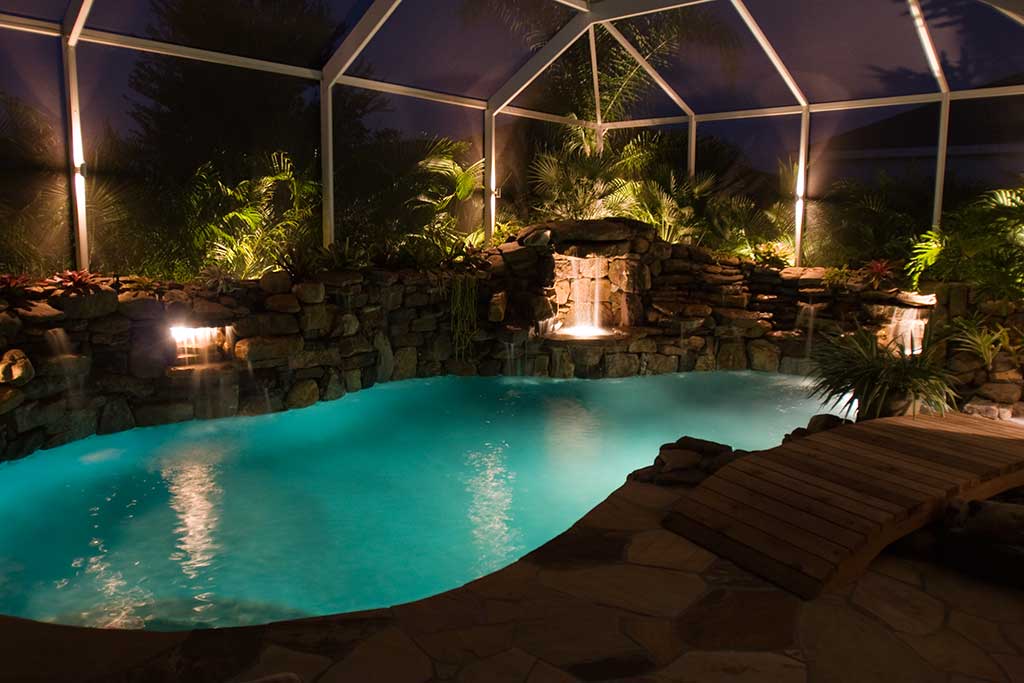 Lagoon pool remodel with multiple grotto waterfalls, bridge and outdoor kitchen designed and built by Lucas Lagoon Inc. in Bradenton, FL